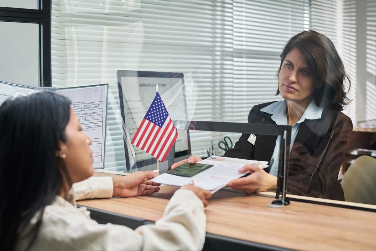 Middle Aged Woman Processing Documents for Young Adult Woman at Visa Center